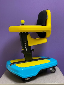 a bright yellow and blue powered mobility device. It has a tray with a central joystick, pommel seat, platform for the child's feet, and four small caster wheels. It can be driven in sitting or standing.